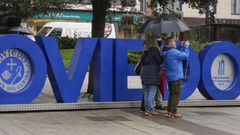 Turistas ante las letras de Oviedo bajo la lluvia