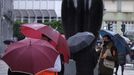 Unos turistas se protegen de la lluvia junto a una estatua de �rculo, en Oviedo