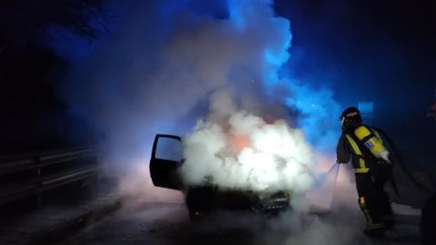 Bomberos trabajan en la extinci�n de un incendio declarado en un coche en Llanes