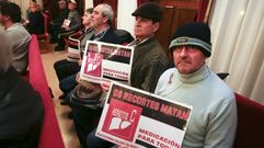 Asistentes al pleno exhibieron carteles pidiendo fondos para el tratamiento de la hepatitis C