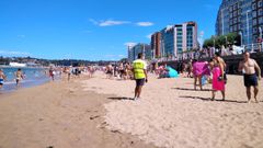 Un acomodador ordena a los ba�istas en la playa de San Lorenzo, con la Polic�a Local de Gij�n, al fondo