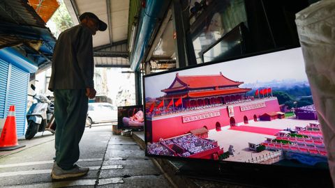 Un ciudadano mira en una televisi�n el desfile militar chino