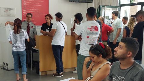 Migrantes esperando su turno en un edificio institucional luso.