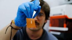 El investigador Yigit Sozen sostiene un chip en un trozo de piel