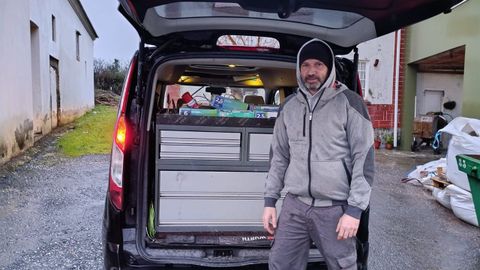 �scar se guarece de la lluvia bajo el port�n de la furgoneta de trabajo