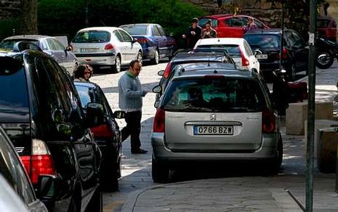 Varios transe�ntes pasan entre los coches aparcados en la plaza de Azc�rraga. 