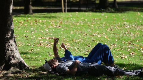 Una pareja descansa en el csped en el parque de Ferrera de Avils