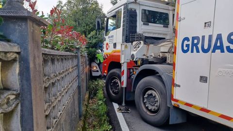 Los operarios intentando elevar el camin encajado frente a villa Julia, en Bergondo