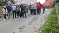 Varios vecinos posan entre los baches que se cuentan por decenas en el camino por que lleva a sus viviendas. 