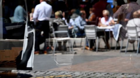 Reflejo de una urna de las votaciones a las elecciones generales, frente a una terraza, en Pola de Siero