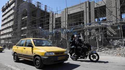 Un coche pasa ante un edificio afectado por bombardeos en Teher�n