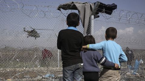 Un grupo de nios observa un helicptero desde un campamento de refugiados en Idomenia, Grecia