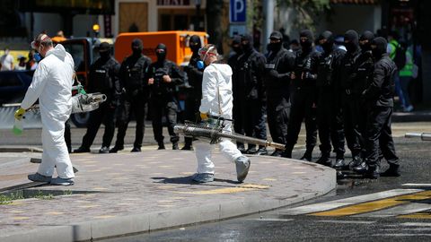 Trabajadores con equipos de desinfección se dirigen a un edificio mientras la policía se prepara para supervisar una manifestación en Kazajistán