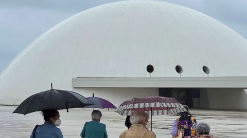 Turistas se protegen de la lluvia en el Centro Niemeyer