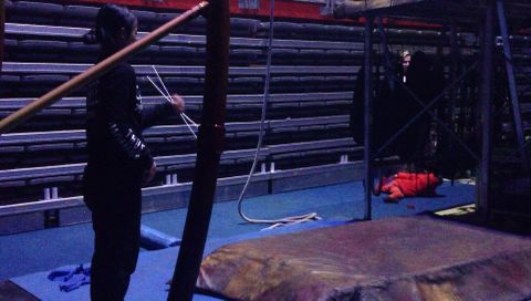 Una artista ensaya su n�mero mientras un ni�o descansa sobre las colchonetas de la trasera de escenario