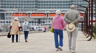 Cruceristas caminando por la Marina con el Iona de fondo