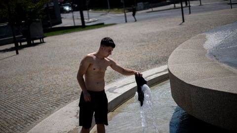 Un joven se refresca en una fuente de Praga.