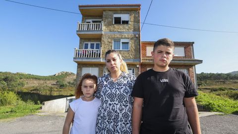 Leticia, junto a sus dos hijos, ante el edificio en el que residen en Arou, Camarias