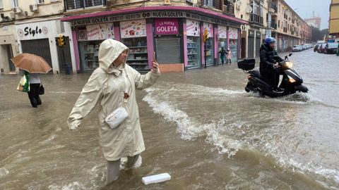 Una mujer hace fotografas, con el agua hasta las rodillas, en la ciudad de Mlaga, que sufri inundaciones a causa de las fuertes precipitaciones de este mircoles.