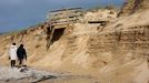 Dos vecinos de la zona paseaban el jueves por la playa de A Lanzada, en O Grove, al lado de una duna sobre la que se encuentra el paseo de madera arrasado. La arena est� cubierta de residuos.