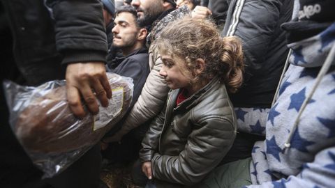 Una ni�a espera la ayuda que les prestan organizaciones humanitarias en un campamento frente a la frontera polaca.