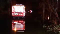 El veh�culo de los bomberos, reflejado en el agua, que cubr�a la calzada, y el autom�vil al fondo