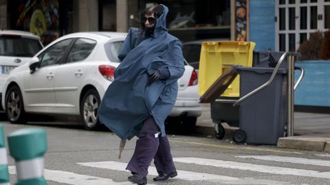 Una mujer camina envuelta en un chubasquero por A Coru�a