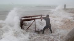 Un hombre trata de recuperar del mar una de las mesas de su restaurante que se ha llevado el mar tras el devastador paso del hurac�n �Mar�a�