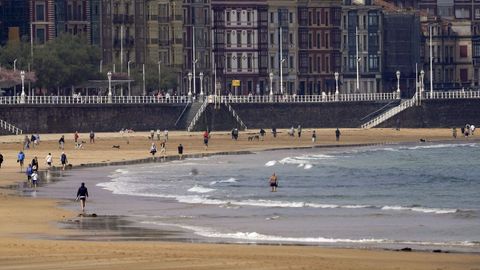 Paseantes a la orilla de la playa de San Lorenzo en Gijón (Asturias)