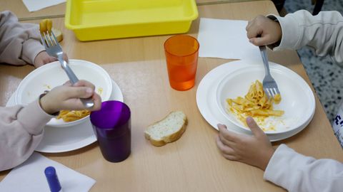 Dos peque&ntilde;os en un comedor escolar en una foto de archivo