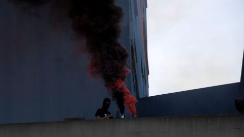 Un joven con la cara tapada explota un bote de humo, durante la manifestación de CSI, SUATEA, CNY y CGT, por el Primero de Mayo, en Gijón