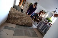 Dolores Miguens levanta la alfombra para mostrar unas baldosas que nunca se han arreglado. 