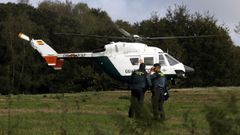 Un helic�ptero que participa en la b�squeda posado en un prado de la localidad de San Cibrao, pr�xima a la de A Ra�a
