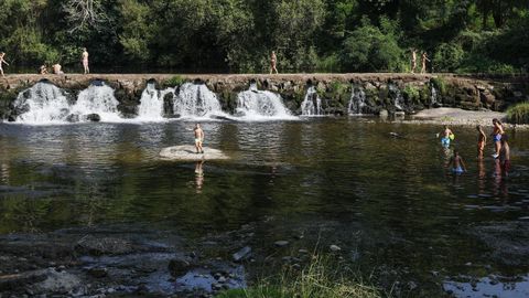 Varias personas, la mayora nios, se refrescan en el rea recreativa A Veronza, en el ro Avia