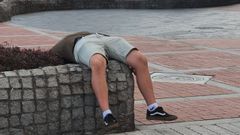 Hombre dormido en el paseo de la playa de Poniente, en Gij�n