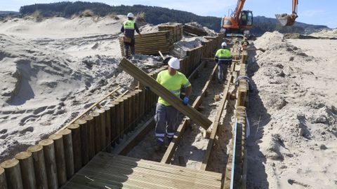 Varios operarios trabajaban ayer en el montaje de una de las pasarelas de madera que da acceso a la playa, junto al patio del colegio