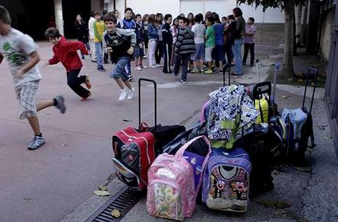 Mochilas con material escolar se acumulan en el patio de un colegio durante un recreo.