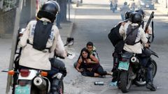 Agentes de seguridad rodean a dos manifestantes afectados por un ataque con bombas lacrim�genas