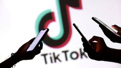 Adolescentes, consultando sus m�viles con el logo de TikTok de fondo.