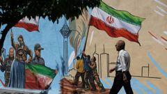 Un iran� pasa por delante de un grafiti propagand�stico en una calle de Teher�n
