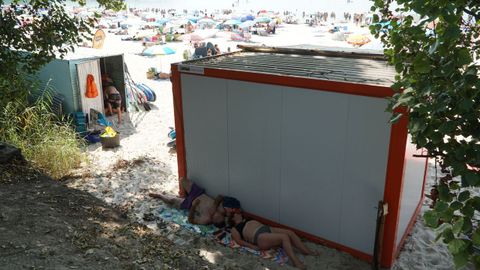 Personas tumbadas a la sombra en una playa de Bueu
