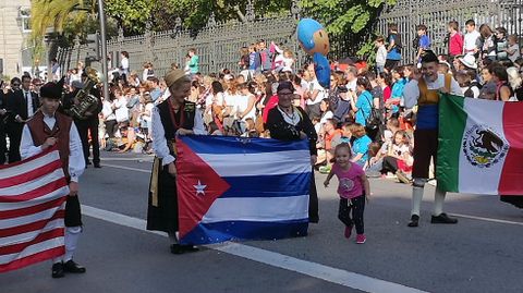 Una nia entrega un global a las jvenes que sostienen la bandera de Cuba en el Desfile del Da de Amrica en Asturias.Una nia entrega un globo a las jvenes que sostienen la bandera de Cuba en el Desfile del Da de Amrica en Asturias