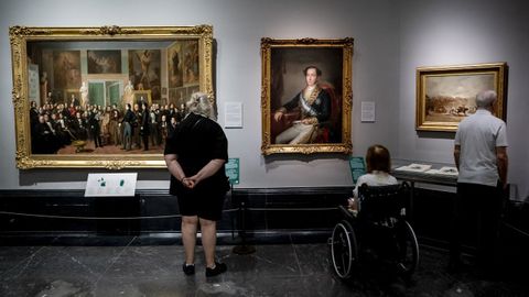 Tres asistentes observan varias obras en el Museo del Prado, en Madrid. 
