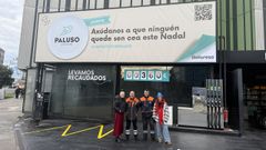 Chus Iglesias y Graciela Castro con dos empleados de la Galuresa junto a la valla de la campa�a solidaria.