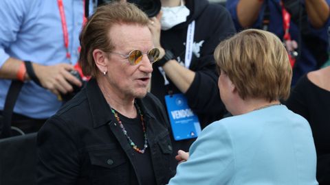 El cantante Bono saluda a la excanciller alemana Angela Merkel