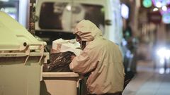 Imagen de archivo de un indigente rebuscando en un contenedor en la calle Orz�n de A Coru�a