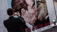 Un visitante fotograf�a un grafiti en la East Side Gallery de Berl�n