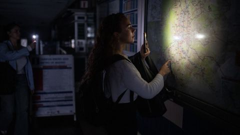 Una mujer consulta un mapa de la red de Metro con la linterna de su m&oacute;vil el d&iacute;a del apag&oacute;n
