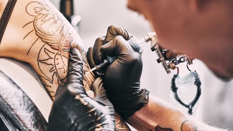 Un tatuador realiza un tatuaje.