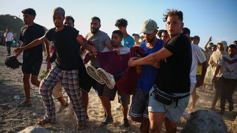 Migrantes cargan a otro migrante que result� herido.